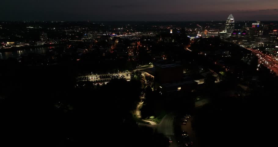 Aerial view of the illuminated Cincinnati Art Museum amidst the dark cityscape, contrasting with the bright city lights in the background, Cincinnati, Ohio, United States.
