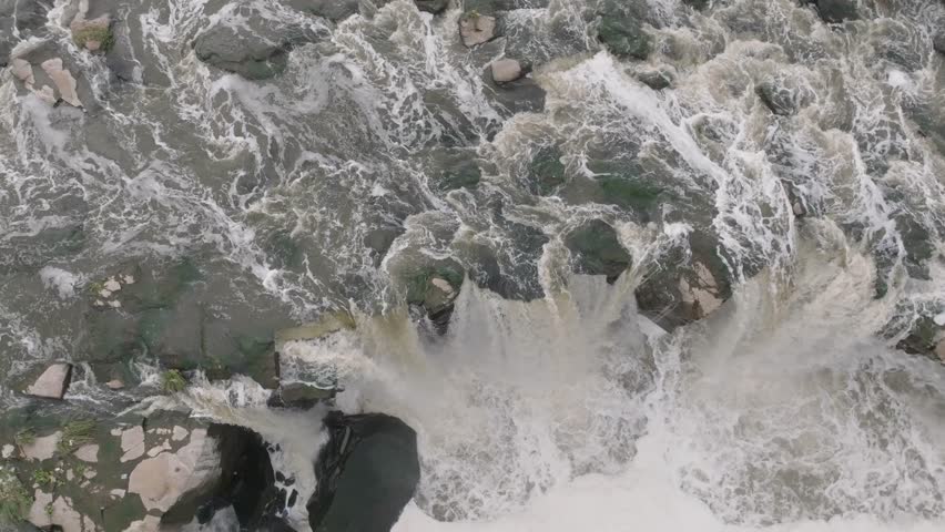 Aerial view of powerful water cascading down over jagged rocks, creating a mesmerizing display of nature