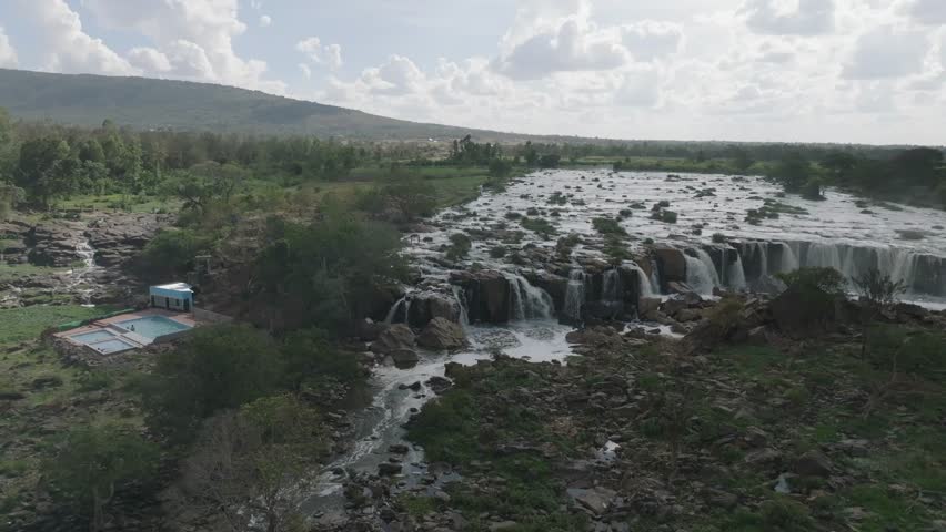 Aerial view of a cascading waterfall with white water contrasting against dark rocks and green vegetation near Kilimambogo, Kiambu County, Kenya.