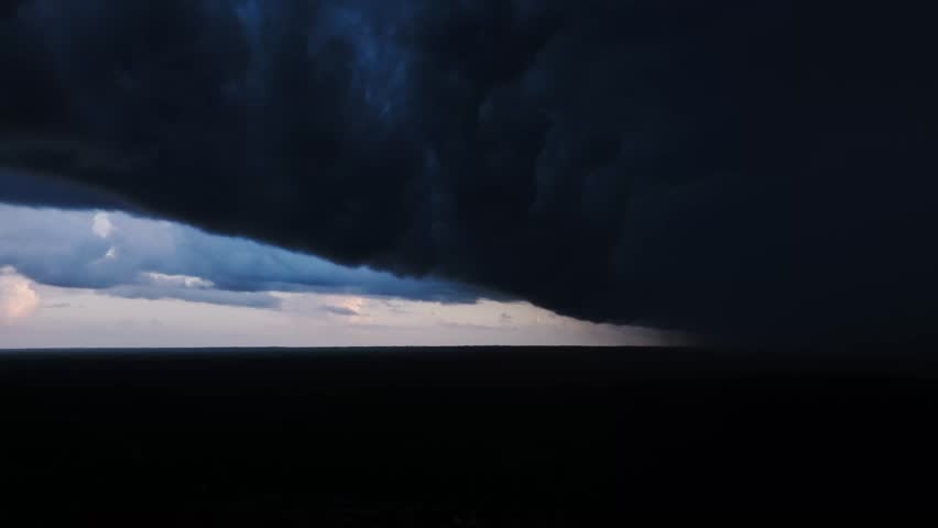 Dark clouds consume sky while distant rain reveals nature’s raw power and drama