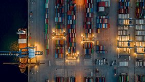 Aerial overhead motion time lapse view of a illuminated container terminal dock with loading and unloading activity by cranes and trucks off cargo ships during evening  - Powered by Shutterstock - Get 15% off with code: PIKWIZARD15
