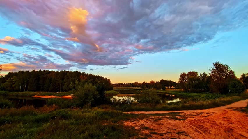 Countryside Landscape With Gauja River and Forest Under Vibrant Cloudscape at Sunset in Latvia