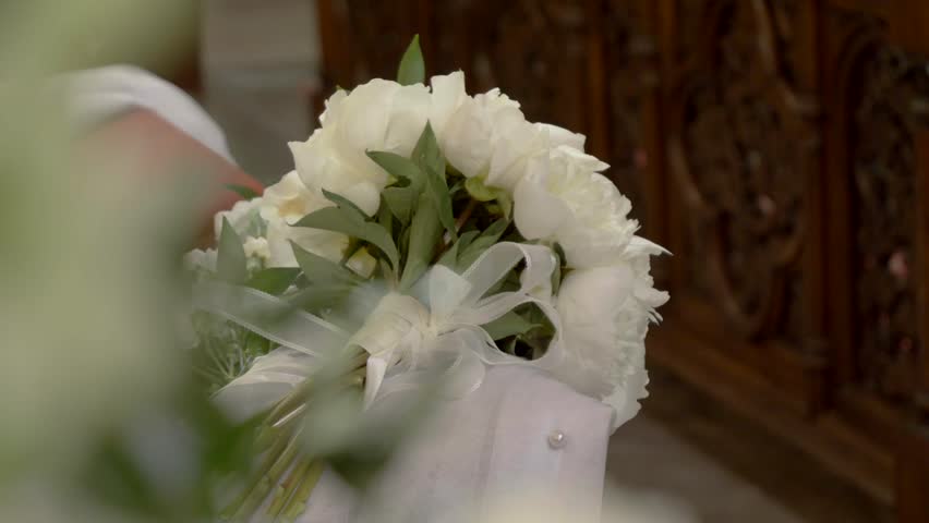 Close-Up of White Rose Wedding Bouquet on Kneeler in Church