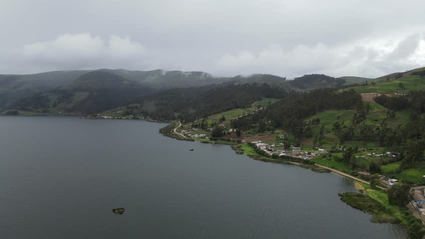 A stunning aerial view of a peaceful lagoon surrounding a small Peruvian village, where nature and tradition meet in perfect harmony under the Andean sky
