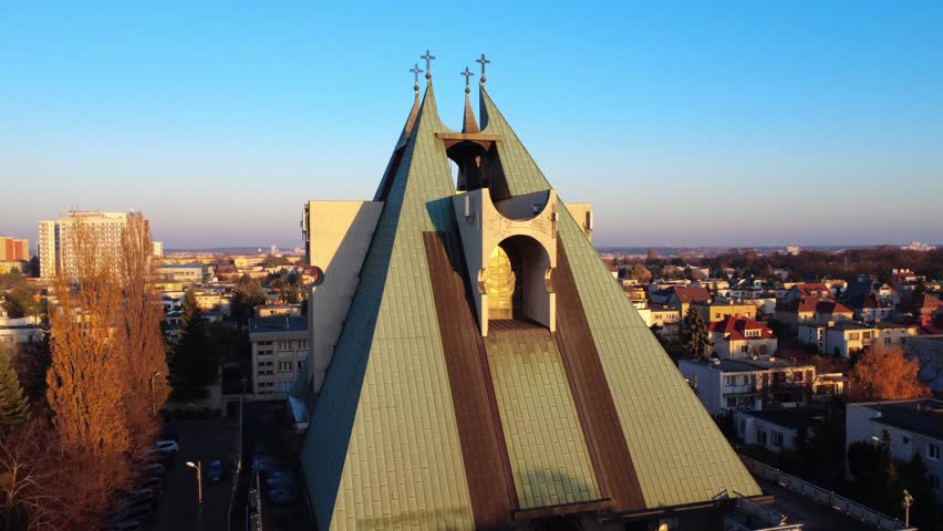 Aerial circular close-up orbit around the Church of Sts. John Bosco at sunset in Poznan, Poland, captured during golden hour.