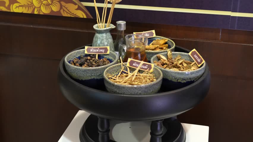 A tray of dried herbs, roots, and oils in labeled bowls at Wat Pho, Bangkok. Represents the study and practice of Traditional Thai Herbal Medicine, wellness, and ancient healing knowledge.