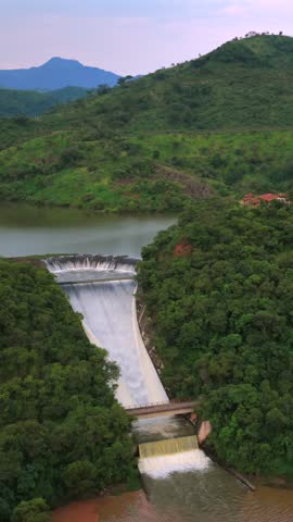 Vertical aerial view of El Carrizo Dam overflowing through spillway surrounded by forest and mountains in Jalisco, Mexico