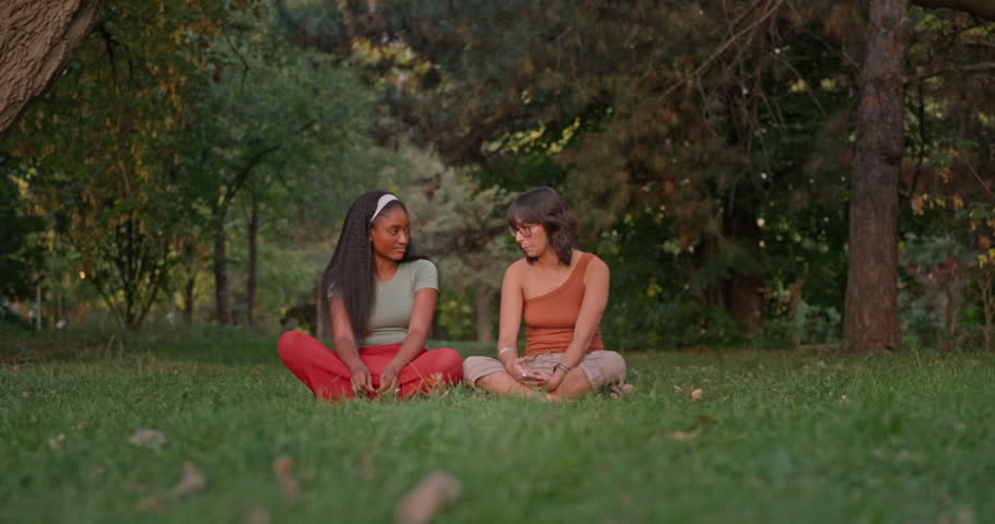 A young Black woman hugs and comforts her white friend in a peaceful forest scene showing empathy diversity and emotional support in nature.
