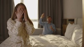 Young couple arguing in bedroom during tense relationship conflict, angry woman gesturing emotionally, boyfriend sits in background, showing couple argument, relationship conflict, emotional tension - Powered by Shutterstock - Get 15% off with code: PIKWIZARD15