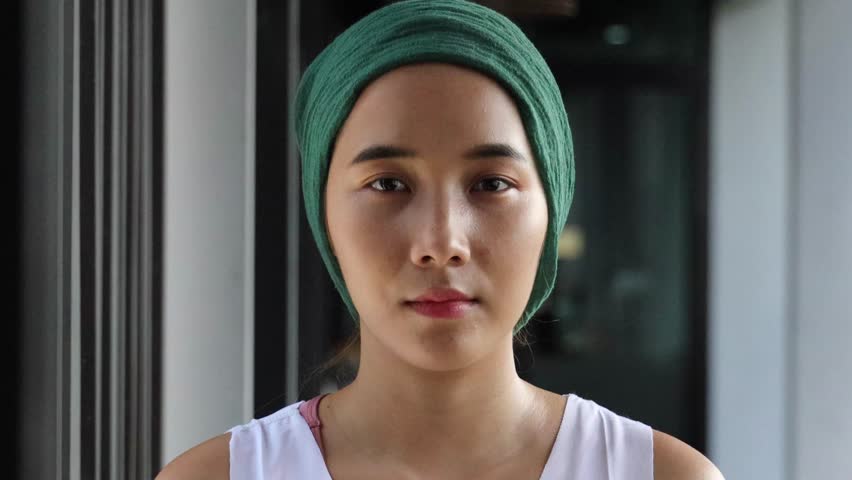 Confident encouraged hopeful healthy asian woman cancer patient with head scarf getting a good cure in rehabilitation facility, real female person model