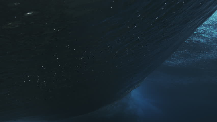 Powerful ocean wave separates itself from water as sparkling dazzling textured surface is broken in vortex