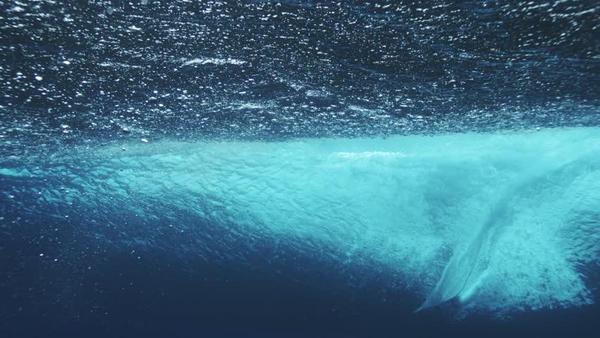 Incredible dazzling air bubbles float in super slow motion, underwater wave breaking from behind