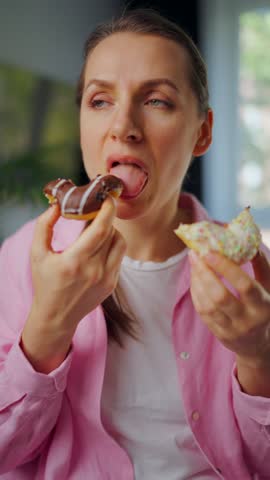 Woman with eating disorder eating two donuts with pleasure and at the same time