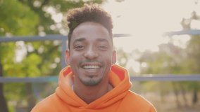 Close up young smiling happy joyful man he wear orange hoody casual clothes looking camera walking rest relax in spring green city park go down sunshine alley outdoors on nature. Urban leisure concept - Powered by Shutterstock - Get 15% off with code: PIKWIZARD15