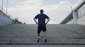 Male athlete with prosthetic leg standing at the bottom of outdoor stairs, preparing for a workout and running challenge, rear view. - Powered by Shutterstock - Get 15% off with code: PIKWIZARD15