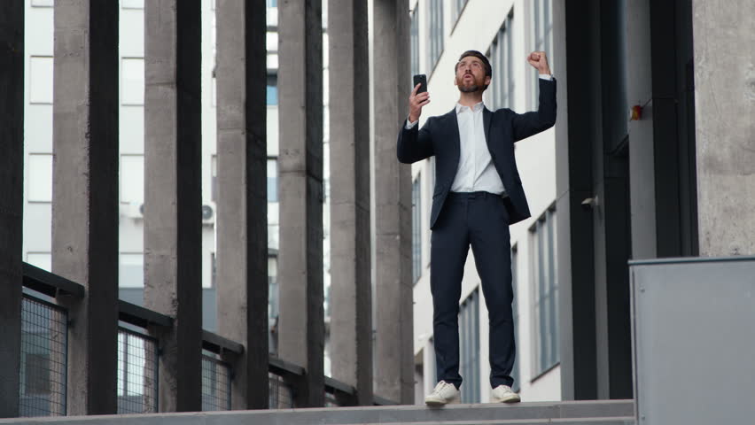 Successful happy mature Caucasian business man businessman win with phone betting jumping celebrating online internet winning male entrepreneur near office building downtown receive offer notification - Powered by Shutterstock - Get 15% off with code: PIKWIZARD15