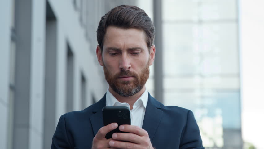 Adult Caucasian businessman holding smartphone mobile phone in city business man using modern technology app outside office middle-aged male employer with telephone remote communication chat working - Powered by Shutterstock - Get 15% off with code: PIKWIZARD15
