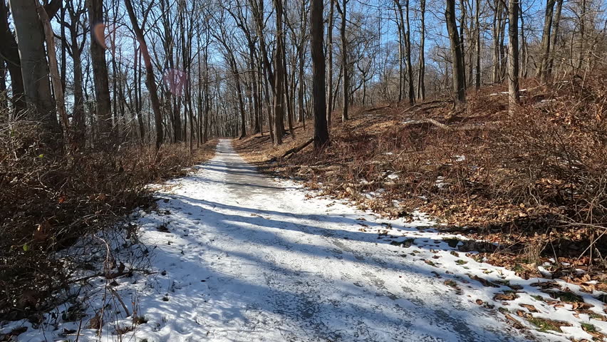 hiking on snowy and icy trail in park on sunny January day