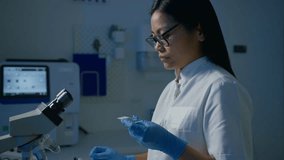 Female laboratory technician pipetting blood sample on the slide, preparing specimen for microscope examination, slow motion shot. Blood testing concept. - Powered by Shutterstock - Get 15% off with code: PIKWIZARD15
