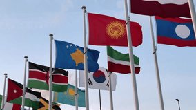 Many colorful national flags wave on a breezy day, with South Korea, Kenya, Kazakhstan, Kyrgyzstan, and Jamaica prominently visible, symbolizing global unity and cultural diversity. - Powered by Shutterstock - Get 15% off with code: PIKWIZARD15