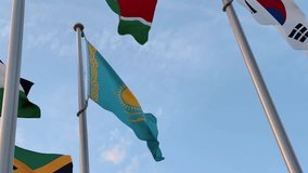 The flag of Kazakhstan flutters proudly under a clear sky, representing the nation's growing voice and presence on the global political stage amid other world flags. - Powered by Shutterstock - Get 15% off with code: PIKWIZARD15