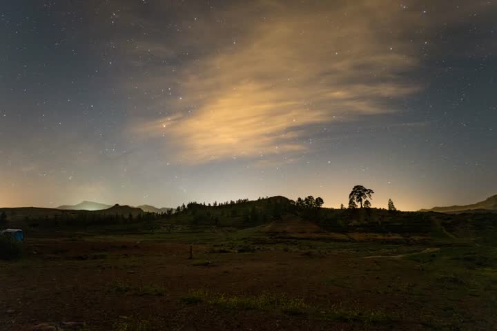 Vía Láctea en movimiento sobre la Presa de Las Niñas, Gran Canaria. Reflejos en el agua, luces del camping y cielo estrellado en timelapse nocturno.