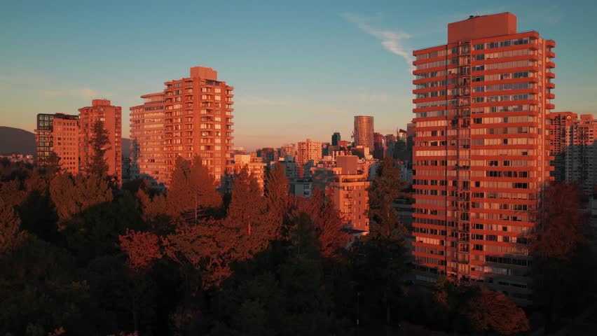 Low rising aerial shot of skyscrapers adjacent to Stanley Park at sunset in downtown Vancouver, British Columbia, Canada. 4K