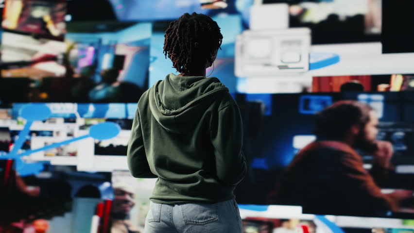 Jolly woman doing conference presentation in front of audience, showing clips on digital videowall. Smiling influencer using mic to talk about content creation and social network experiences, camera B