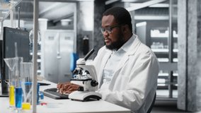 Lab scientist using microscope to evaluate cellular structures. African american man observes specimens through magnification tool at laboratory bench, advancing scientific knowldege, camera B - Powered by Shutterstock - Get 15% off with code: PIKWIZARD15
