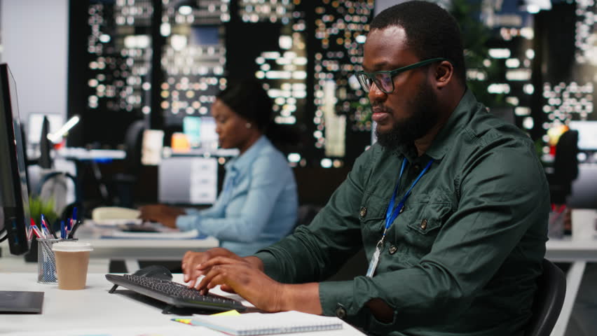 Black coworkers team monitoring forecast data for a new monthly analysis in dark office, utilizing reports and insights to plan reports and statements. Goal setting after hours. Camera B.