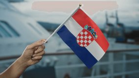 Hand holding croatian flag on a boat during a seaside cruise, symbolizing national pride in an outdoor setting with a male's hand visible against a maritime backdrop. - Powered by Shutterstock - Get 15% off with code: PIKWIZARD15