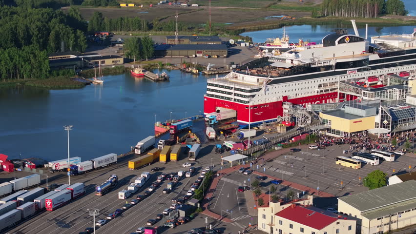 Aerial view of a large cruise ship docking at the port of Turku, Finland. Passengers, trucks and cars are disembarking the ship as tourists wait to board