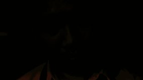 Close-up, dramatic portrait of a Southeast Asian man looking directly at the camera with an intense, creepy expression, illuminated by sharp, low-key red and blue police emergency lights. - Powered by Shutterstock - Get 15% off with code: PIKWIZARD15