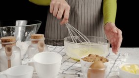 Close-up of a woman whisking butter mixture in a glass bowl, surrounded by baking ingredients like brown sugar, flour, and eggs on a kitchen counter - Powered by Shutterstock - Get 15% off with code: PIKWIZARD15