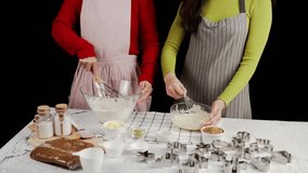 Two people preparing cookie dough together, whisking ingredients in glass bowls surrounded by baking tools and cutters, capturing a warm homemade baking atmosphere and collaborative kitchen - Powered by Shutterstock - Get 15% off with code: PIKWIZARD15