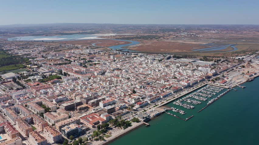 Aerial view drone shot of Portugal Algarve aerial Ria Guadiana estuary meeting Vila Real Santo Antonio harbor with visible marshes, mudflats and marina ecotourism guide perspective