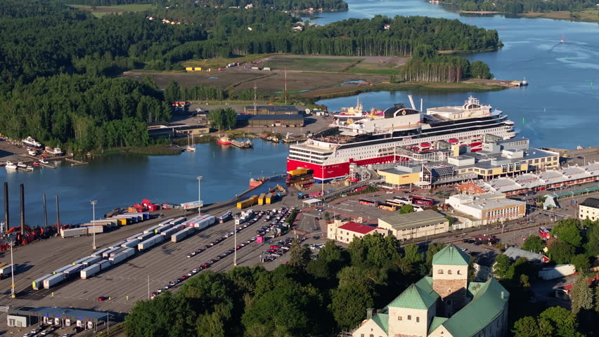 Aerial views capture a large ferry docking at Turku harbor, Finland, surrounded by smaller boats and cargo vessels, showcasing the area