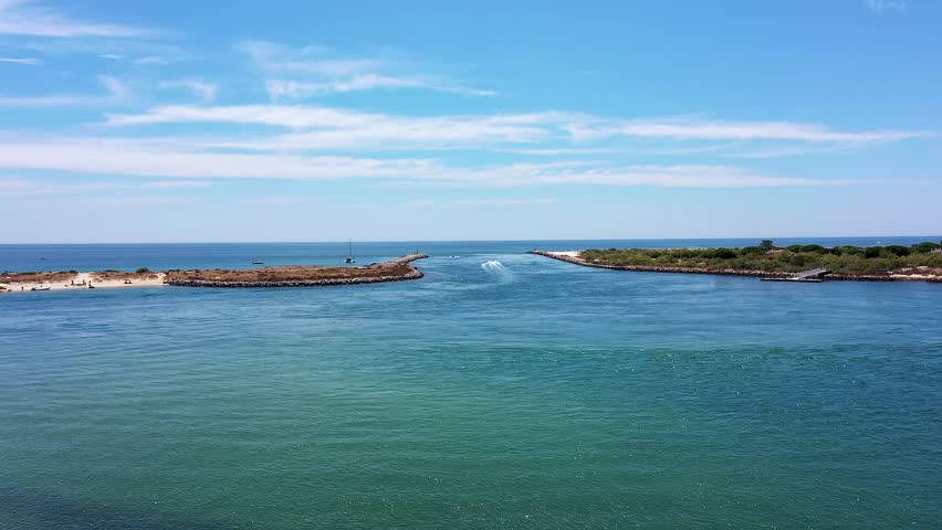 Aerial view drone shot of Tavira Portugal Algarve Aerial sea mouth with breakwater and strong currents, open horizon, clear blue water, passing boats and navigational marks, busy channel