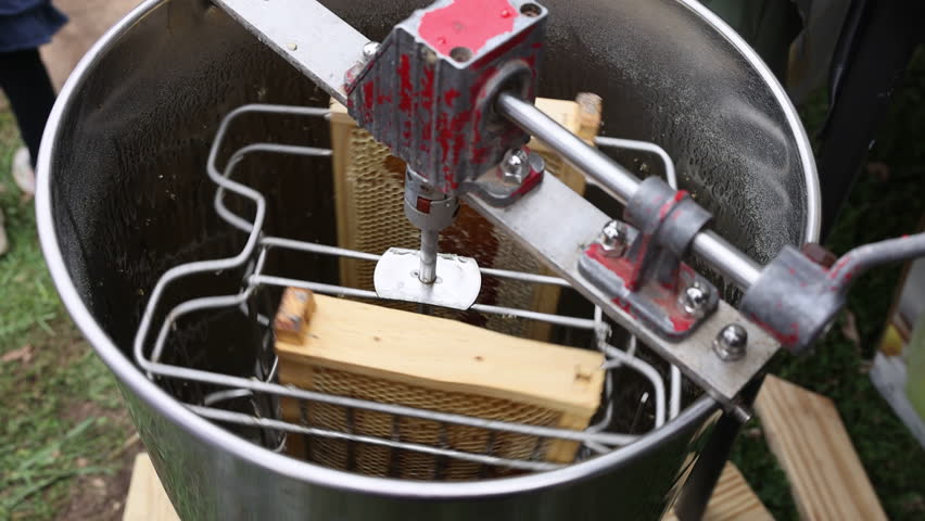 Honey extractor spins frames to separate honey from beeswax at an outdoor beekeeping