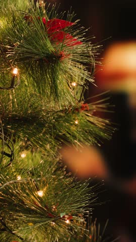 Hand woman decorating on Christmas tree with Christmas glow lights macro, decoration for new year eve.