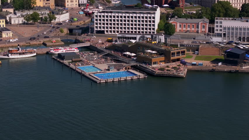 Tourists and locals relax on a swimming pool by the sea in a sunny summer day in Helsinki, Finland, enjoying the harbor