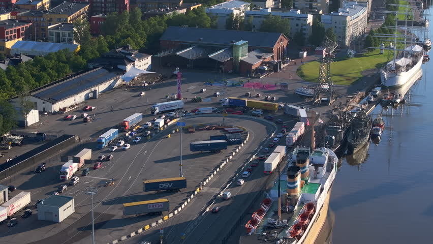 Aerial view showcasing Turku harbor in Finland. Trucks and cars line up, awaiting ferry boarding while a large white ship rests at the pier