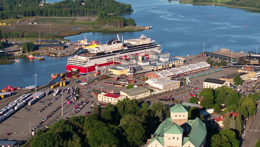 Aerial view captures large cruise ships navigating a bustling harbor in Turku, Finland, while cars and buses move around the port area