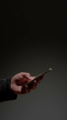 Phone at night, Close-up macro hands of a man scroll news feed on mobile phone app application. Screen of the mobile phone illuminates male hand. 