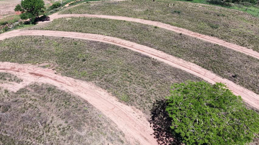 A scenic view of a field and small town at a distance. The natural landscape is composed of dry grass and dirt path.