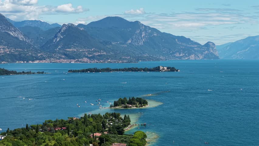Drone video in 4K shows Isola di San Biagio, Lake Garda, Italy, with panoramic views, turquoise water, and Italian landscape.