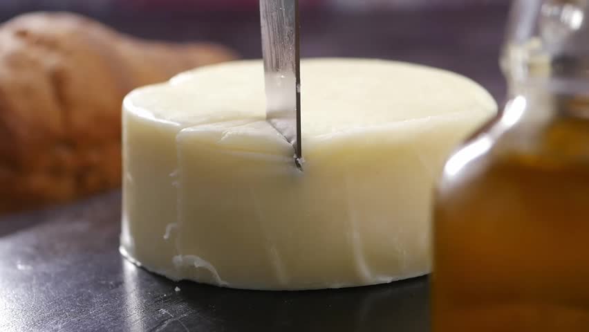 Cutting a fresh cheese wheel with a sharp knife