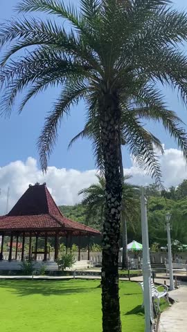 Peaceful tropical resort area with green grass field and wooden huts near Mesra Beach, Gunungkidul, Yogyakarta, Indonesia — calm sunny day atmosphere