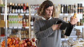 Customer scans the barcode of a bottle of champagne on his phone while standing near the counter and shelves with products in the supermarket. High quality 4k footage - Powered by Shutterstock - Get 15% off with code: PIKWIZARD15