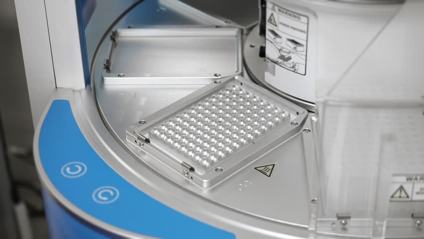Close up of scientist hands placing plastic plate into automated nucleic acid extraction station for PCR testing in modern clinical lab.